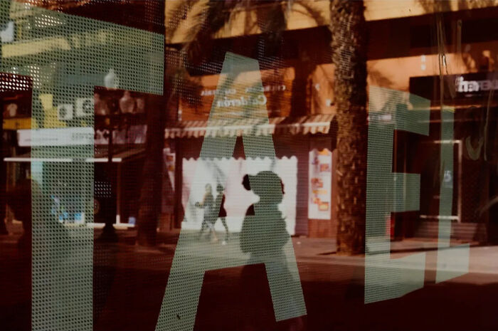 Abstract street photograph by Andrea Pozzoni capturing silhouettes and reflections amidst urban architecture.