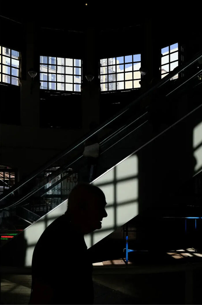 Silhouetted figure on an escalator with abstract street photography shadows by Andrea Pozzoni.