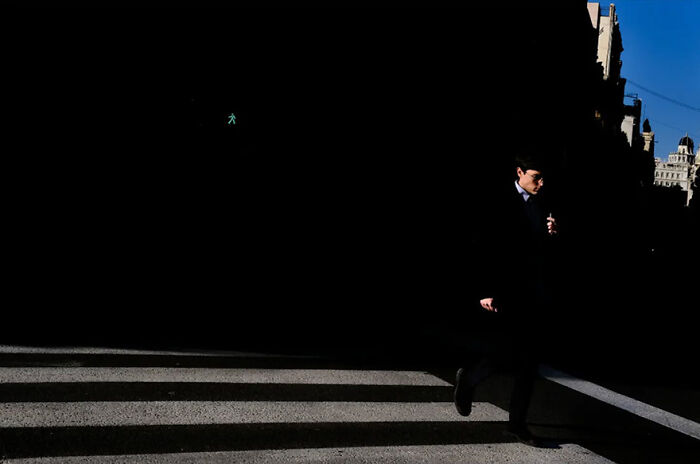 Abstract street photograph by Andrea Pozzoni of a person crossing a dimly lit crosswalk.