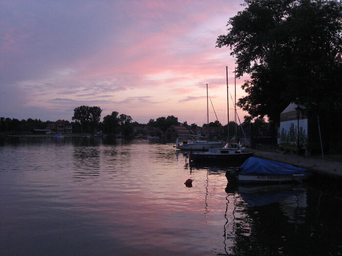 Tranquil waters at sunset with boats docked, illustrating natural wonders.
