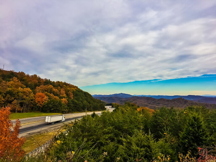 Truck on a scenic highway surrounded by autumn foliage, representing legendary American road routes.