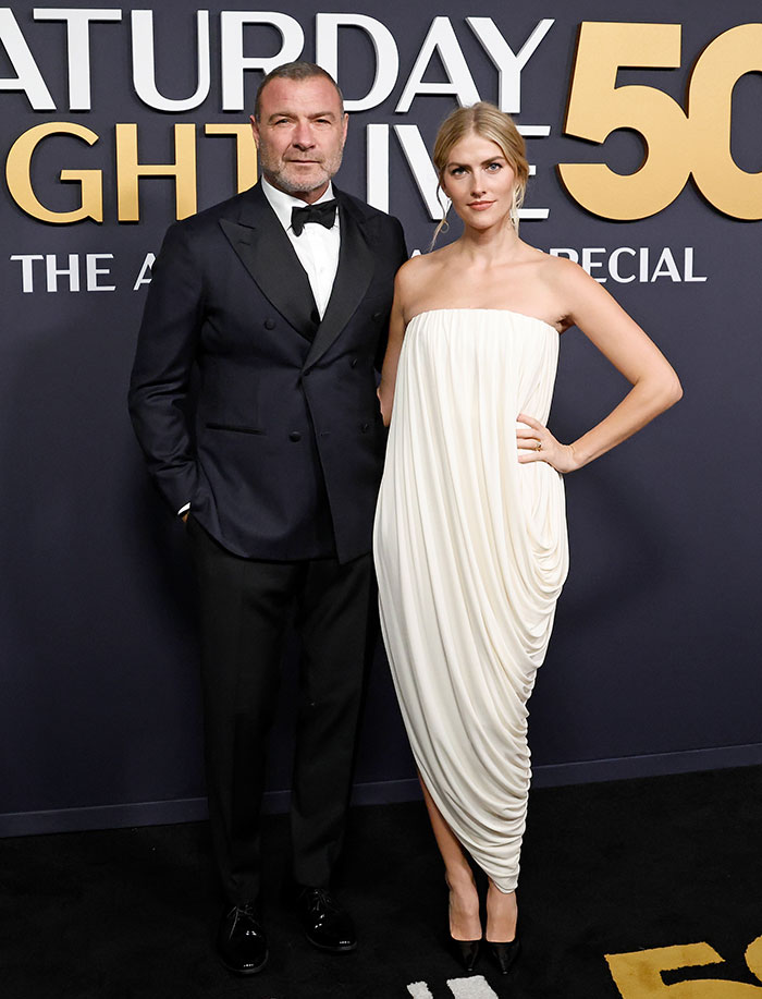 Couple poses in formal attire on the red carpet for SNL 50th Anniversary.