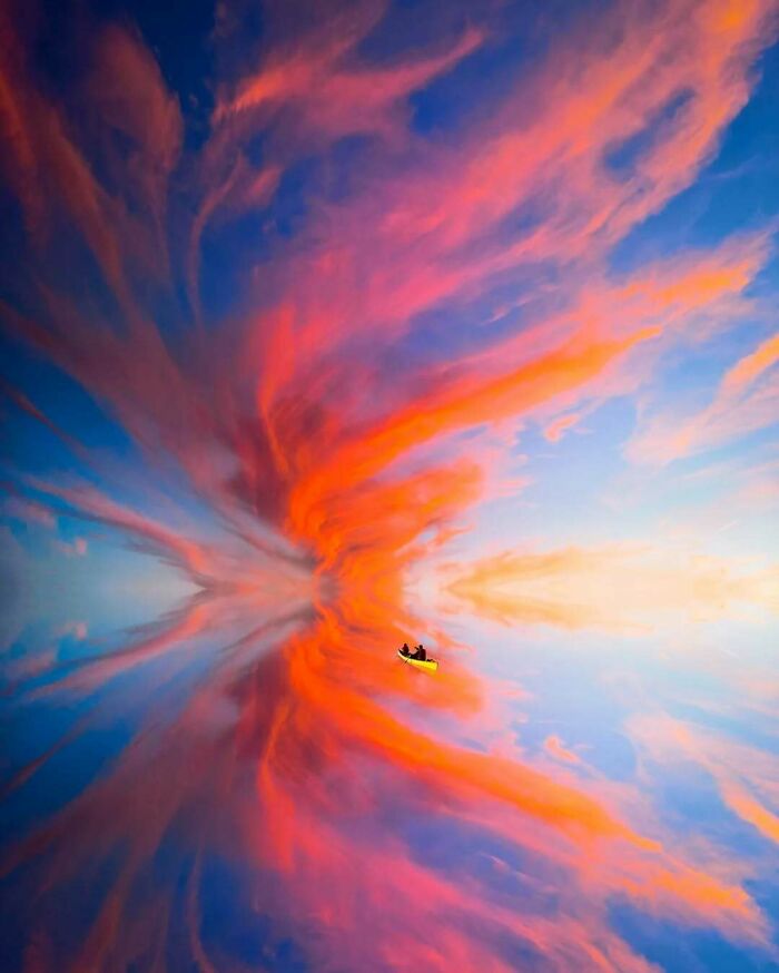 A surreal scene of a person in a kayak amidst a vivid, colorful sky, embodying minimalism and mystery.