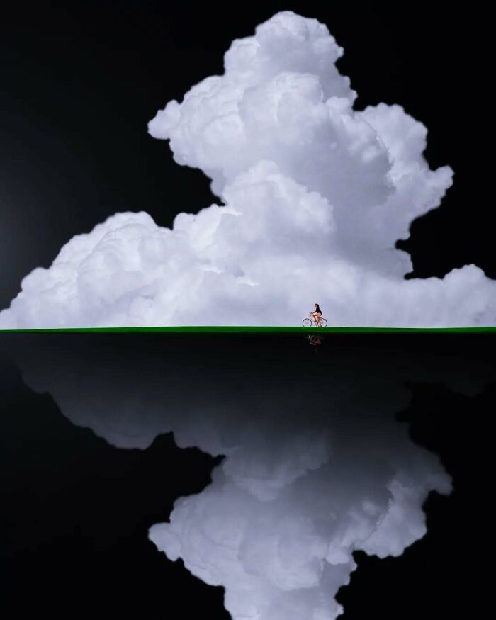 Surreal photo of a person cycling along a cloud-filled horizon, reflecting minimalist magic and mystery.
