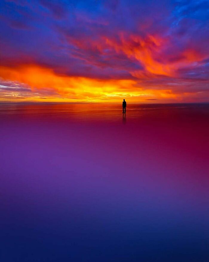A lone figure stands on a surreal, colorful horizon, embodying minimalism and mystery.