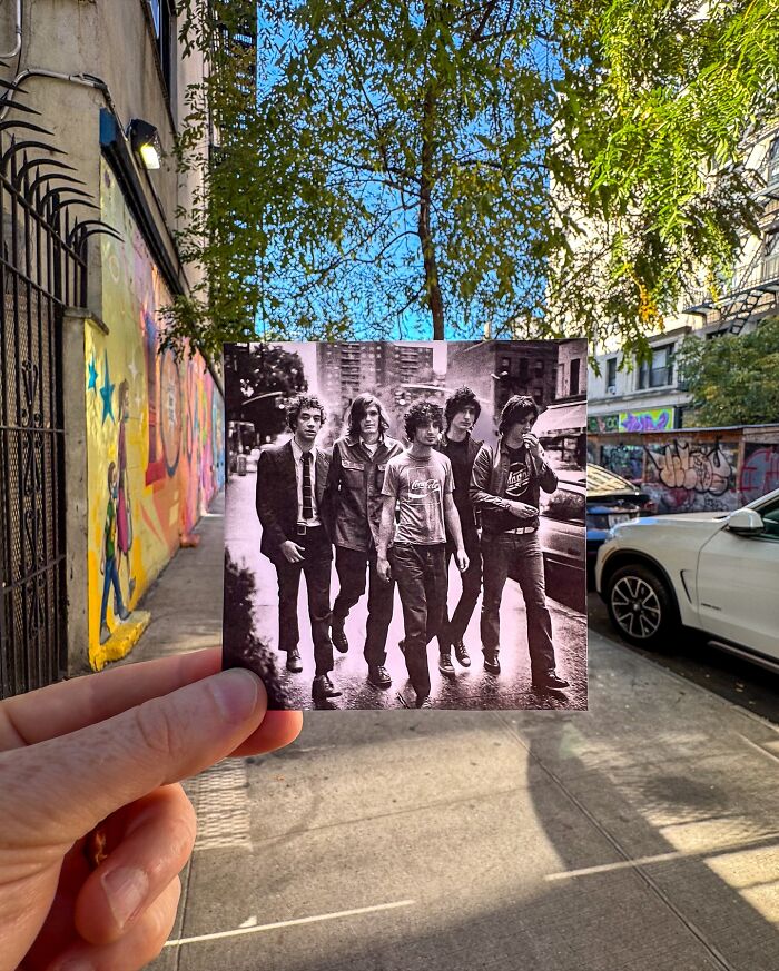 Steve Birnbaum photo of an iconic band held over the same street location, with graffiti and parked cars in the background.