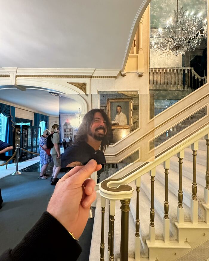 Hand holding a photo of a man in front of a historic staircase, blending past and present iconic locations.