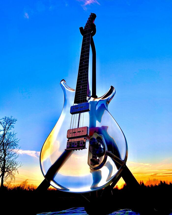 Unique guitar crafted from transparent material, reflecting the sunset sky.