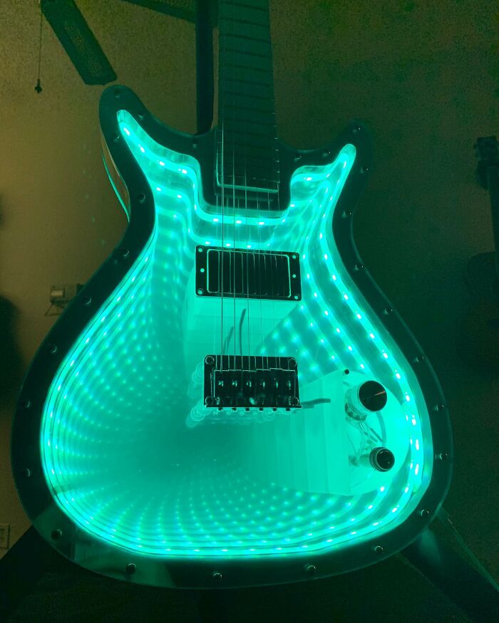 Guitar made from unexpected materials, glowing with green LED lights, showcasing artistic craftsmanship.