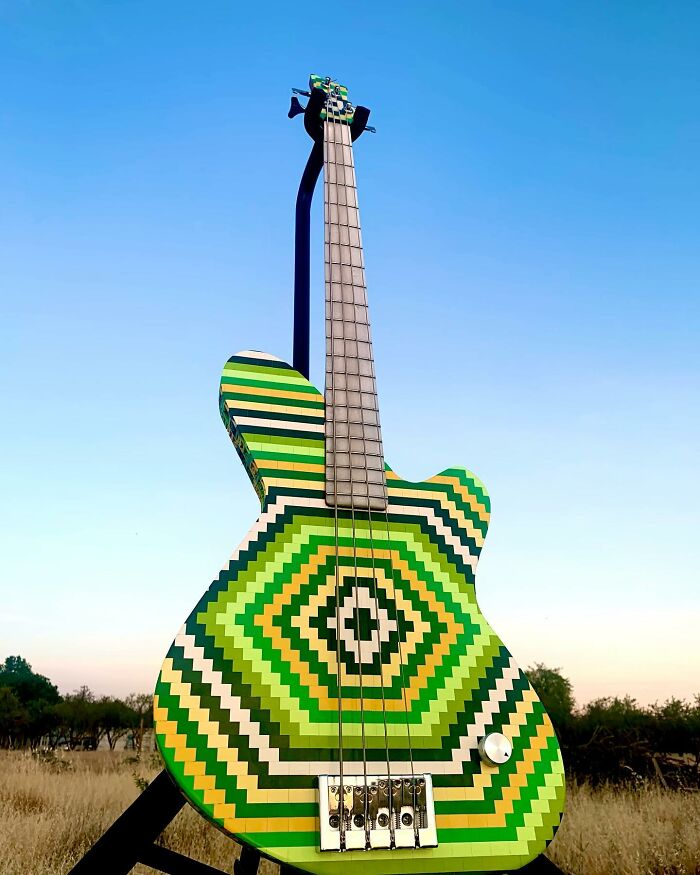 Unique guitar crafted from unexpected materials, featuring a vibrant geometric pattern in a natural outdoor setting.