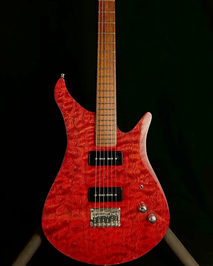 Stunning guitar made from unexpected materials, featuring a unique red pattern and sleek design.