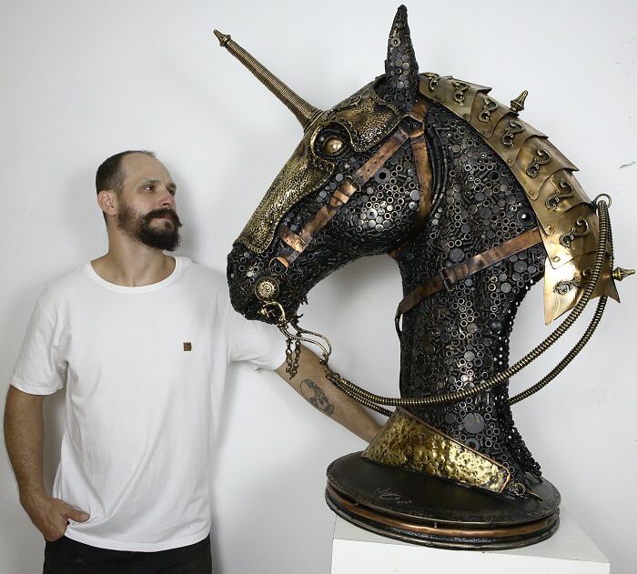 Artist standing beside an incredible scrap metal unicorn sculpture, showcasing intricate craftsmanship.