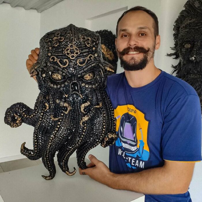 Artist posing with an incredible sculpture made from scrap metal, showcasing intricate design and craftsmanship.
