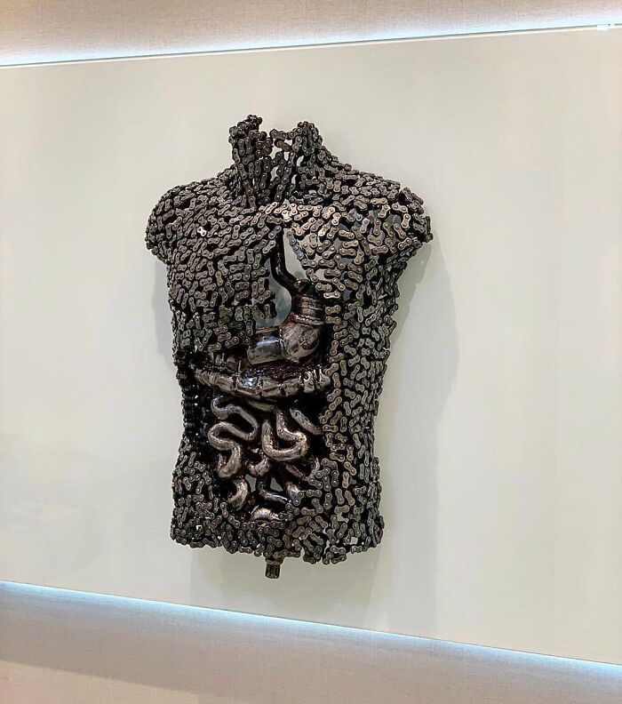 Sculpture of a human torso crafted from scrap metal, showcasing intricate internal structures.
