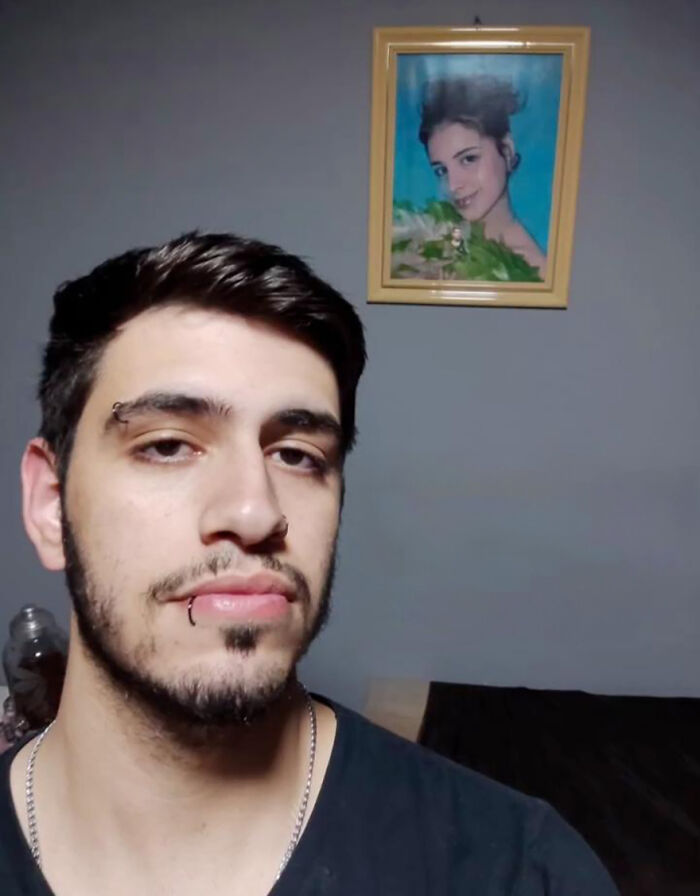 "Man stands in front of a portrait, setting up a family prank for online laughter.