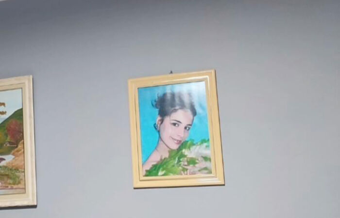 A family prank with a funny portrait of a smiling person in a wooden frame on a plain wall.