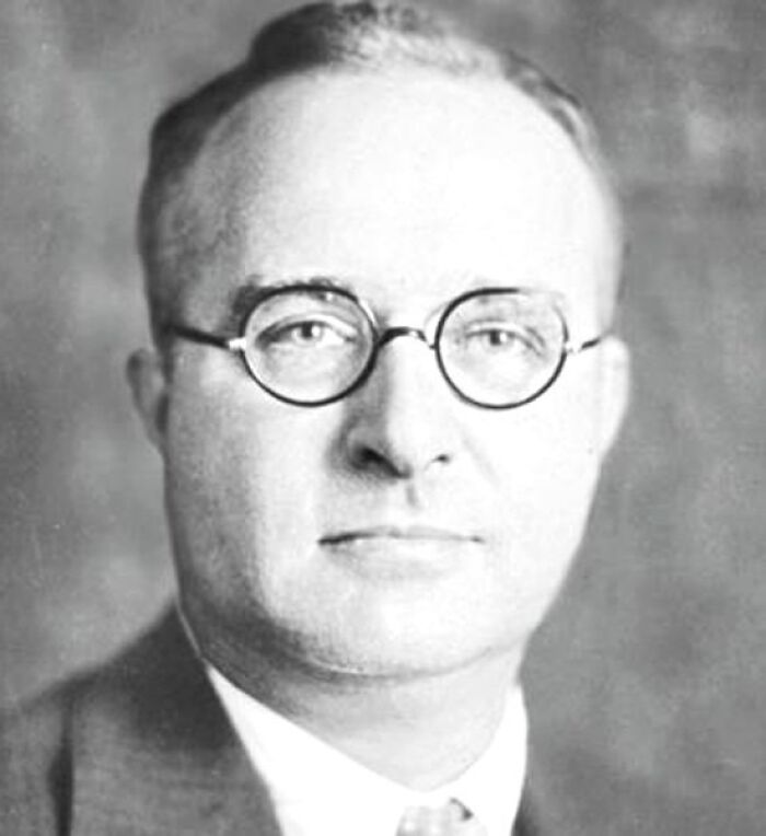 Inventor with glasses in a formal portrait, illustrating the concept of inventions leading to undoing.