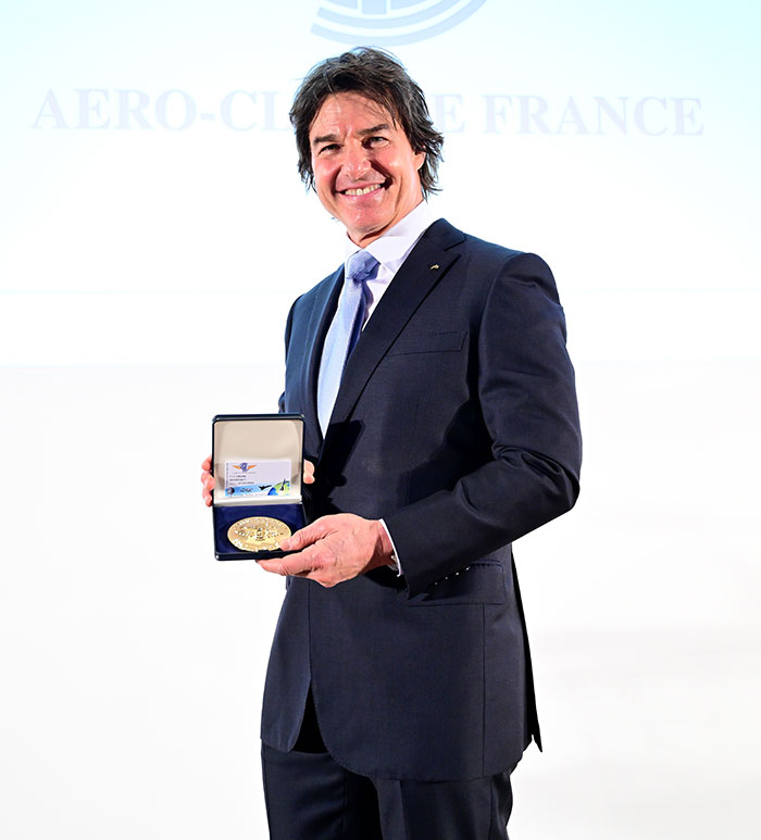 Man in a suit holding an award, smiling at an event, related to discussions about his appearance in Super Bowl 2025.