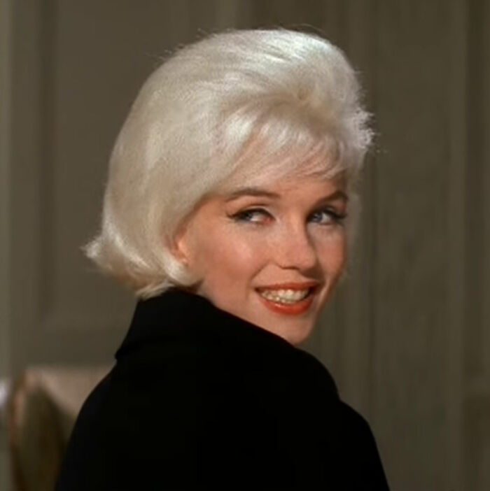 Smiling celebrity with blonde hair looking over shoulder, creating an unforgettable impression.