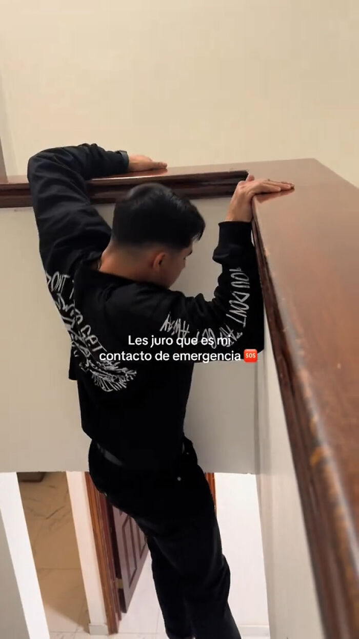 A man in a black sweater hanging from a stair railing, illustrating emergency mishandling humor.
