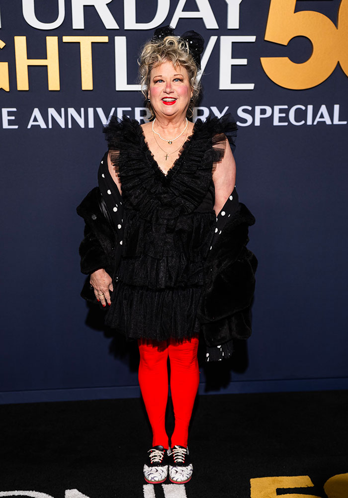 Woman in unique outfit with red tights at SNL 50th anniversary red carpet event.