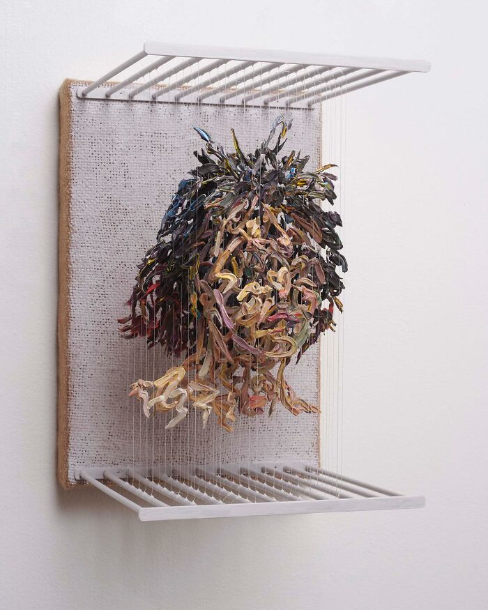 Three-dimensional fragmented painting of a person's head by Chris Dorosz, featuring colorful brushstrokes on a grid.