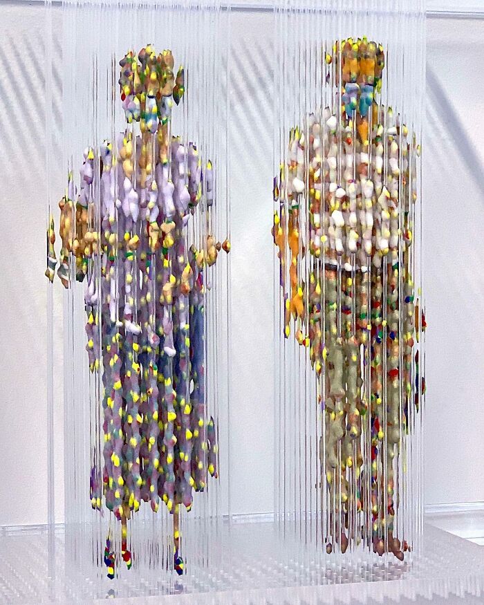Three-dimensional paintings of people by Chris Dorosz, featuring colorful fragmented figures suspended on vertical rods.