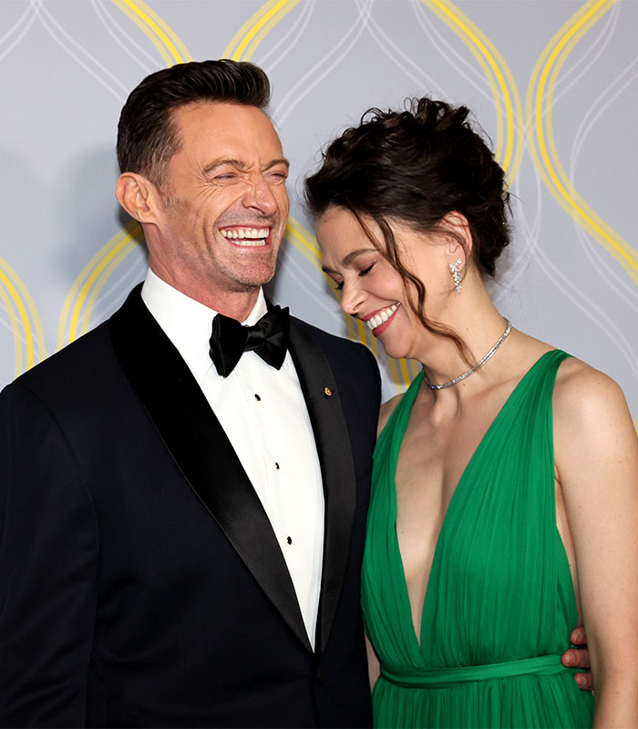 Two people smiling, dressed formally, at an event, feeling happy and relieved.