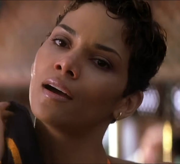Female actor looking concerned, with short hair and hoop earrings, in a close-up shot.