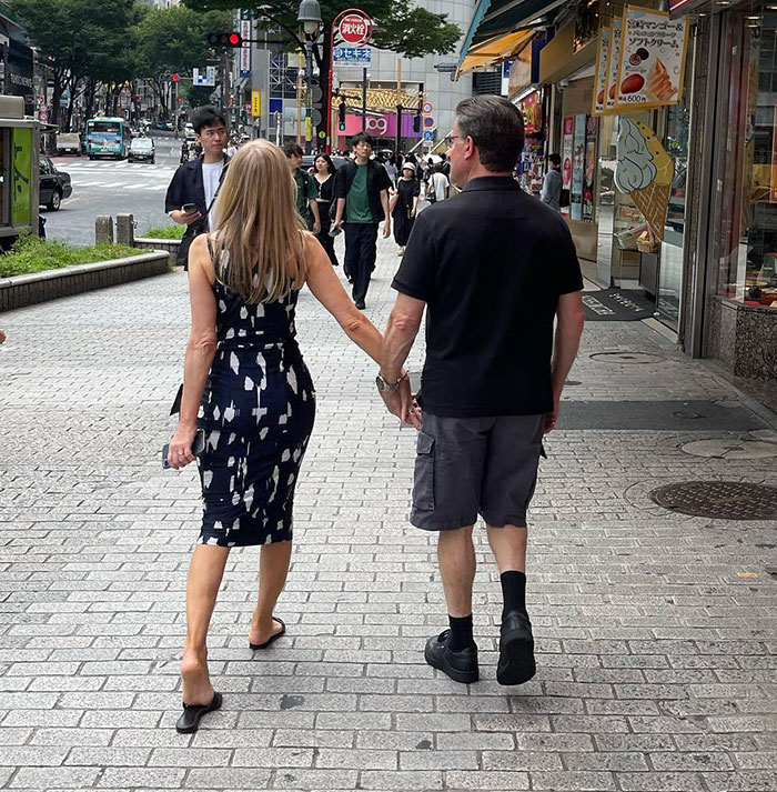 A couple holding hands walking on a busy city street; focus on Bianca Censori's mom. A couple holding hands walking on a busy city street; focus on Bianca Censori's mom.