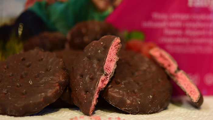 Gluten-free chocolate cookies with a pink filling on a table, associated with Girl Scout cookies. Gluten-free chocolate cookies with a pink filling on a table, associated with Girl Scout cookies.