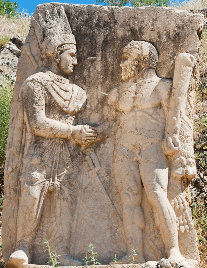 Ancient civilizations' stone relief depicting two figures in a historic handshake, showcasing intricate detailing and craftsmanship.