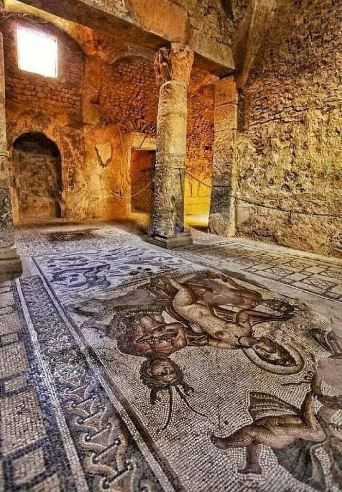 Ancient civilizations' artifacts in a historic site with mosaic floor art and stone columns.