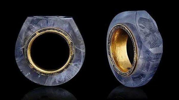 Ancient civilizations artifact: intricately carved blue ring with gold interior, depicting historical engravings.