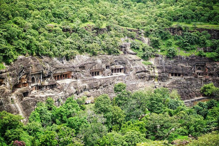 Ancient rock-cut caves nestled in a lush green landscape, reflecting ancient civilizations' architecture and artistry.