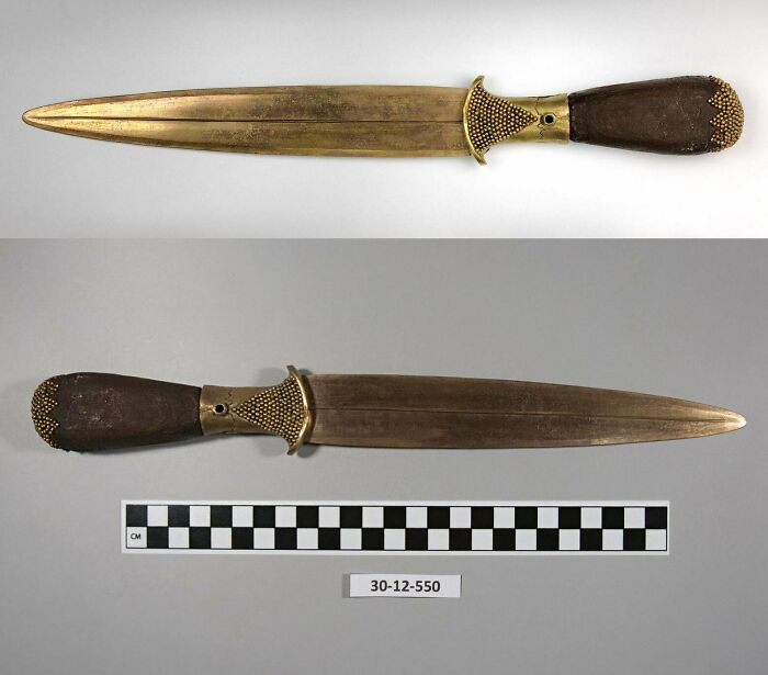 Ancient civilizations artifact: a bronze and wood dagger displayed with a measurement scale.