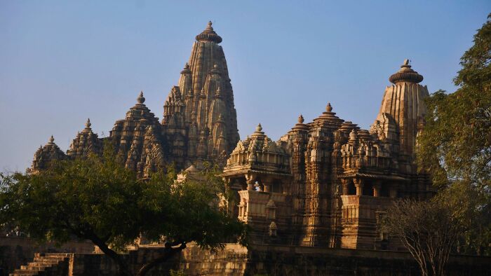 Ancient civilization temples with intricate carvings and spires against a clear blue sky.