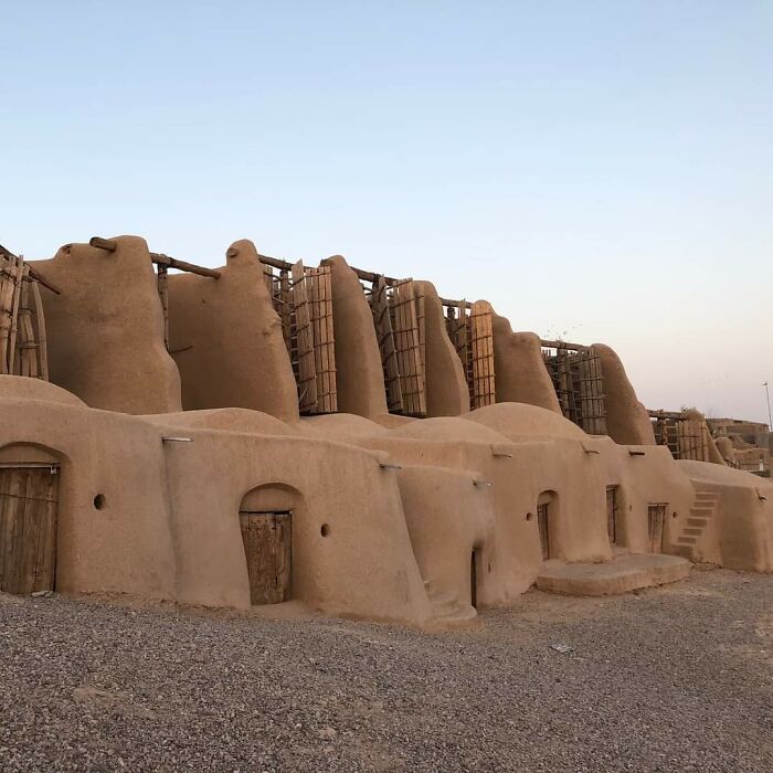 Ancient mud-brick structures with wooden doors, showcasing artifacts of ancient civilizations in an arid landscape.