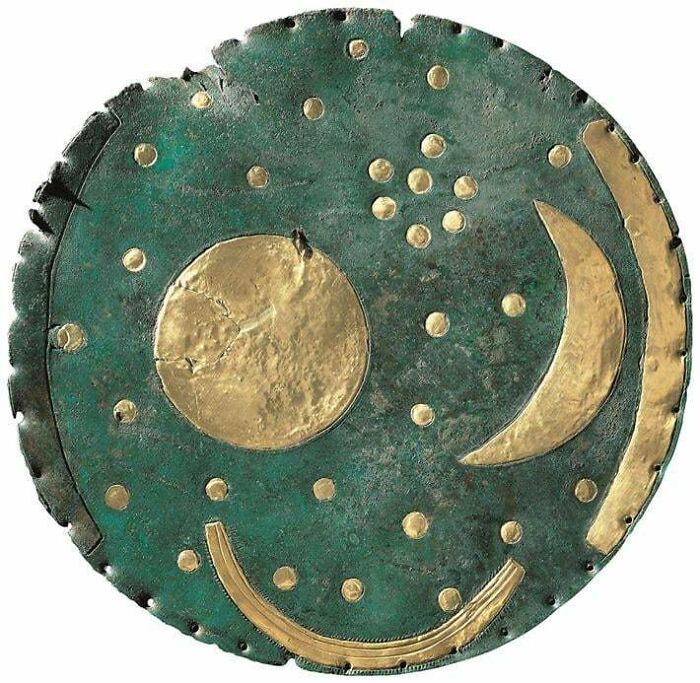 Ancient civilizations artifact depicting celestial bodies on a bronze disc with gold accents.