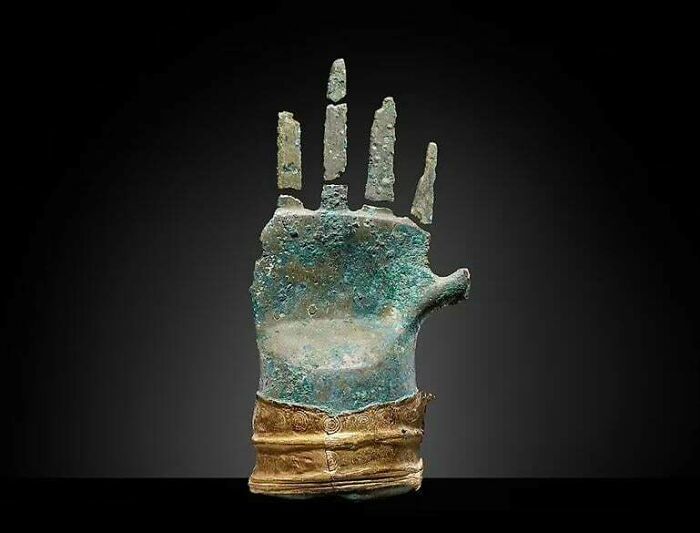 Ancient civilizations artifact: bronze hand with intricate gold detailing, offering historical insight into past cultures.