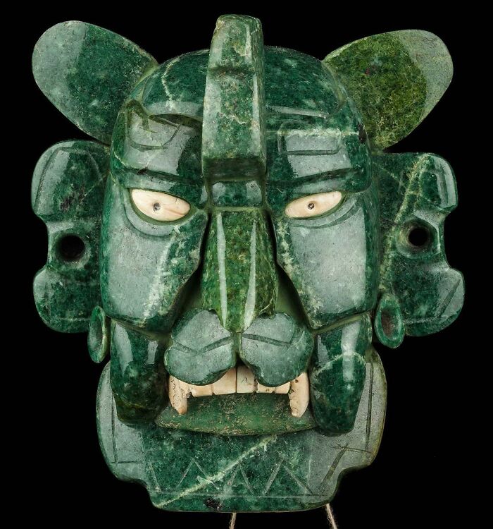 Jade mask showcasing ancient civilizations' artistry with intricate carvings and inlaid eyes.