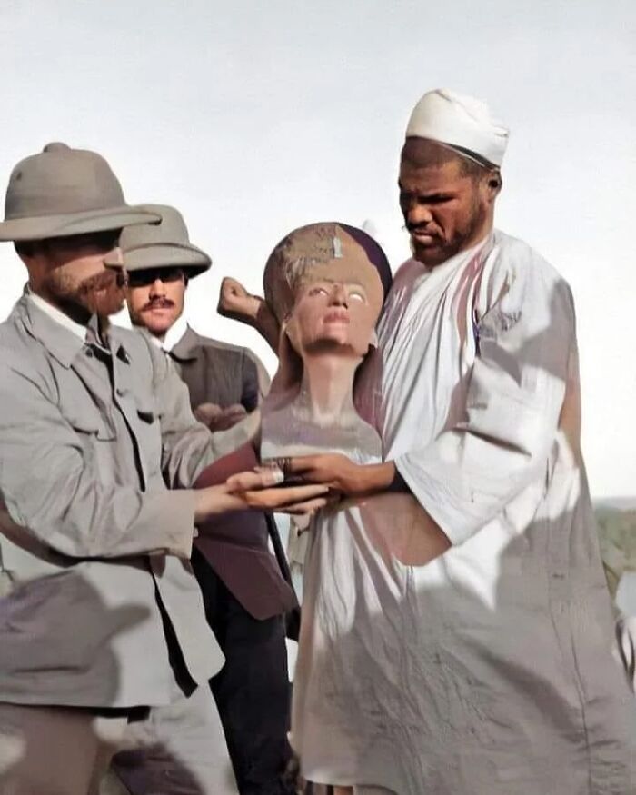 Archaeologists examining ancient artifacts, including a bust, offering a glimpse into ancient civilizations.