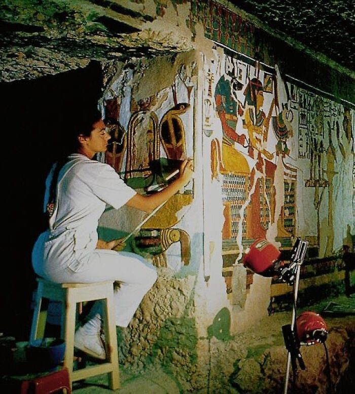 An archaeologist restores ancient civilization artifacts on a mural inside a historical site.