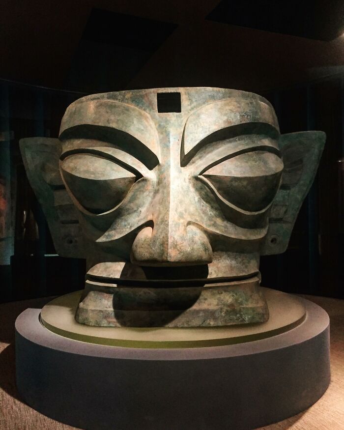 Ancient artifact sculpture with large ears and eyes, offering a glimpse into ancient civilizations, displayed in a dimly lit room.