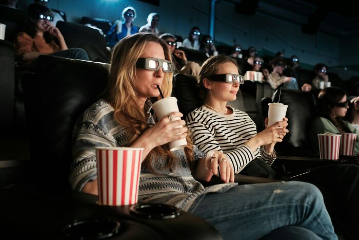 People wearing 3D glasses in a movie theater, immersed in the experience, reminiscent of songs as ringtones nostalgia.