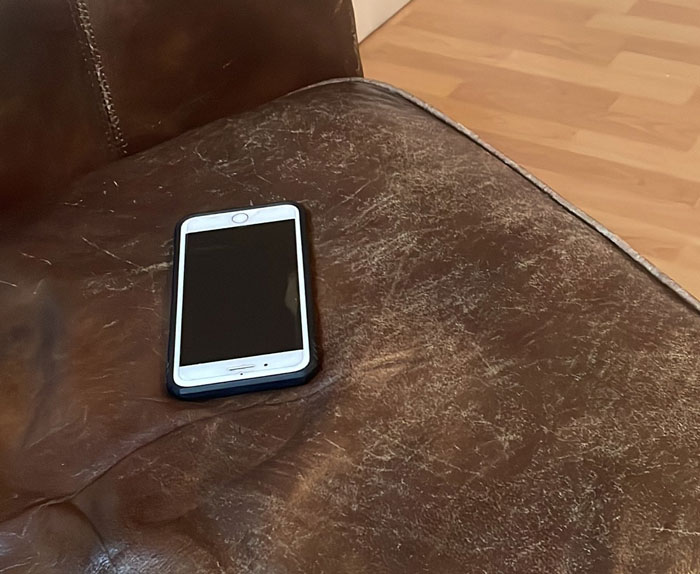 Smartphone left on a worn leather couch, resembling typical behavior of annoying boyfriends and husbands.