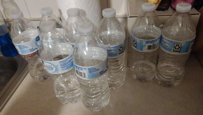 Water bottles cluttering a kitchen counter, left by boyfriends or husbands, causing annoyance.