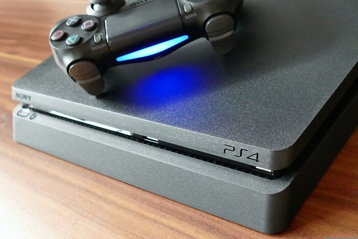 PS4 console with controller, showcasing a multi-functional item ideal for minimalism on a wooden surface.