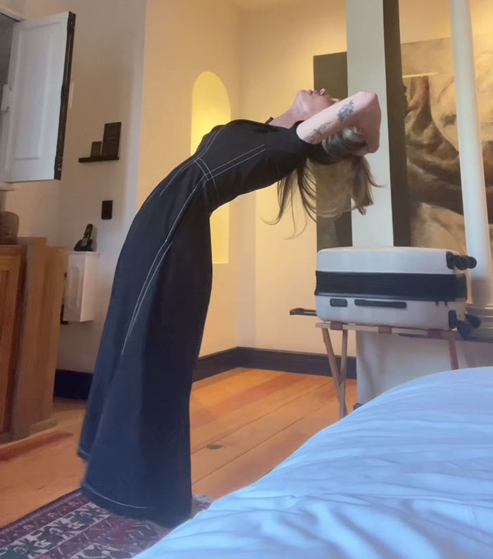 Woman stretching indoors, expressing frustration about rain showers being anti-women.