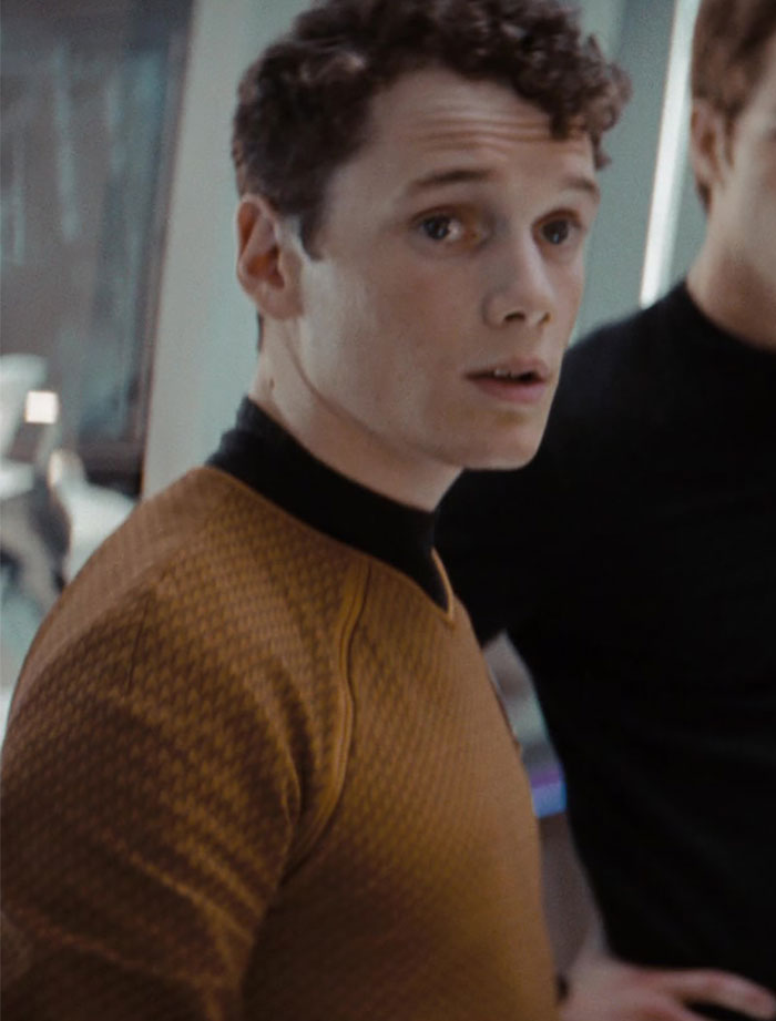 Young man in a futuristic setting wearing a brown textured shirt, symbolizing tragic celebrity losses.